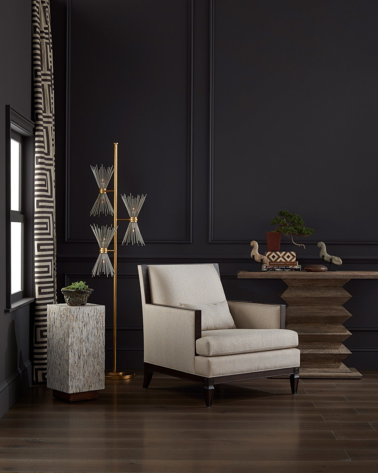 Elegant home decor scene featuring the Novatude Gold Floor Lamp next to a modern chair and decorative side table, enhancing a sophisticated dark-toned room.